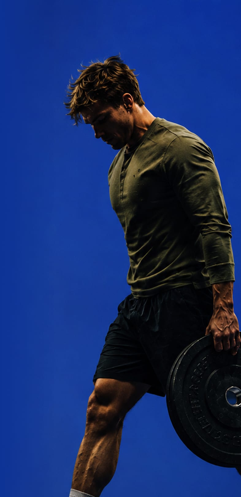 A strength athlete carrying a bumper plate across the gym floor